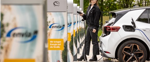 eine Frau steckt ein E-Auto zum Laden an eine Ladesäule an eine Frau steckt ein E-Auto zum Laden an eine Ladesäule an