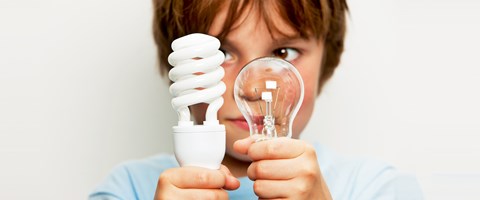 Junge mit Glühlampe und Energiesparlampe Junge mit Glühlampe und Energiesparlampe