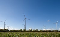 Windkraftanlage vor blauem Himmel auf grünem Feld Windkraftanlage vor blauem Himmel auf grünem Feld