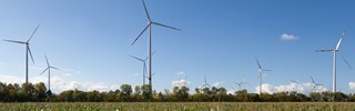 Windkraftanlage vor blauem Himmel auf grünem Feld Windkraftanlage vor blauem Himmel auf grünem Feld