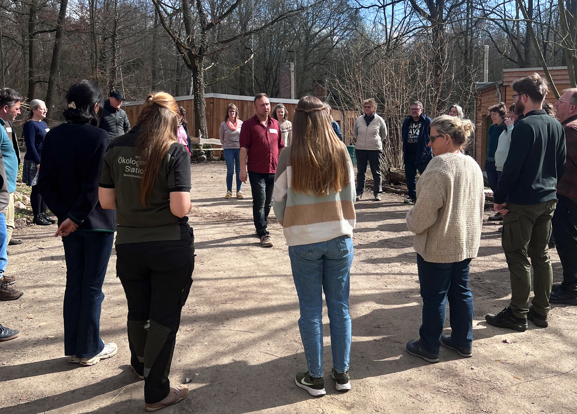 Personen stehen für eine gemeinschaftliche Aktion im Kreis
