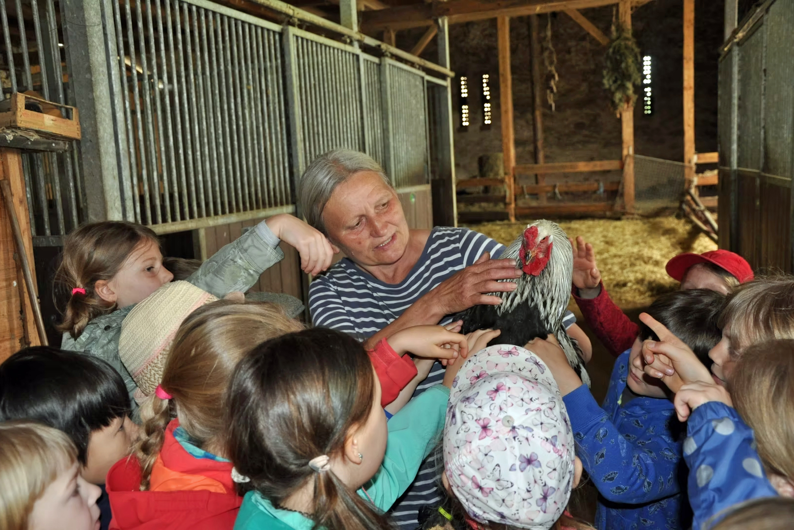 Frau Krasselt auf ihrem Hof mit einem Huhn in der Hand und umgeben von Kindern