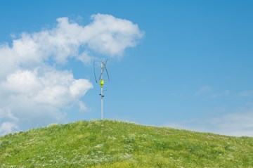 Vertikales Windrad auf grünem Hügel Vertikales Windrad auf grünem Hügel