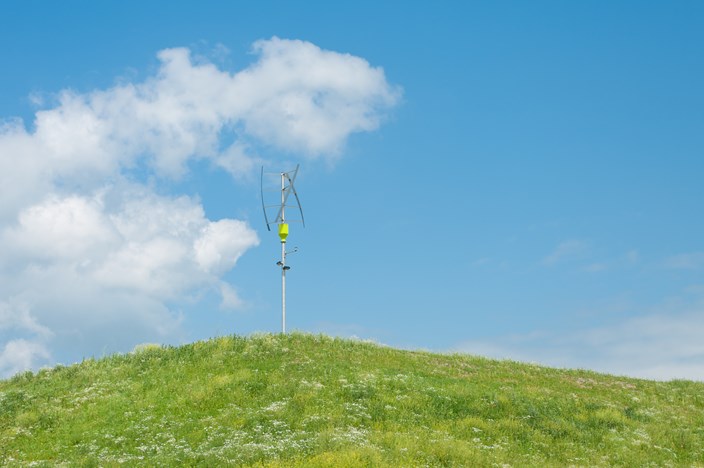 Vertikales Windrad auf grünem Hügel Vertikales Windrad auf grünem Hügel