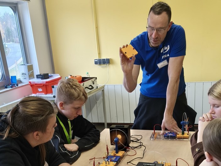 Dozent Michael Bajon erklärt Lucas, Janis und Marie den Kondensator