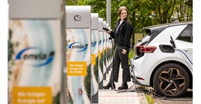 eine Frau steckt ein E-Auto zum Laden an eine Ladesäule an eine Frau steckt ein E-Auto zum Laden an eine Ladesäule an