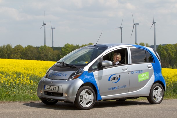 Mitsubishi i-MiEV Elektroauto mit strahlender Fahrerin vor Rapsfeld und Windrädern Mitsubishi i-MiEV Elektroauto mit strahlender Fahrerin vor Rapsfeld und Windrädern