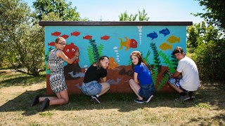 Graffiti-Präventionstag, 4 Jugendliche besprühen ein Verteilerhäuschen mit Aquarium-Motiv Graffiti-Präventionstag, 4 Jugendliche besprühen ein Verteilerhäuschen mit Aquarium-Motiv