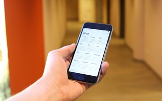 Hand mit Smartphone, auf dem ein Kalender zu sehen ist Hand mit Smartphone, auf dem ein Kalender zu sehen ist