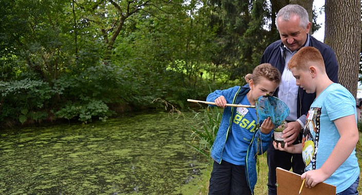 Kinder in der Natur mit einem Lehrer forschen zusammen Kinder in der Natur mit einem Lehrer forschen zusammen