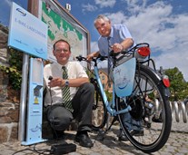2 Männer mit einem Elektrofahrrad an einer E-Bike-Ladestation von enviaM 2 Männer mit einem Elektrofahrrad an einer E-Bike-Ladestation von enviaM