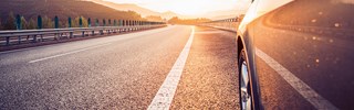 Auto fährt auf einer Straße in den Sonnenuntergang Auto fährt auf einer Straße in den Sonnenuntergang