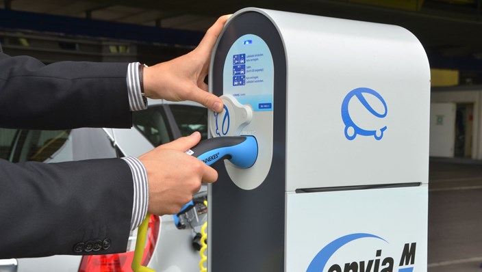 Mann verbindet ein Elektrofahrzeug mit einer Ladestation Mann verbindet ein Elektrofahrzeug mit einer Ladestation