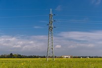 Ein einzelner Freileitungsmast auf einer Wiese unter dunkelblauem Himmel Ein einzelner Freileitungsmast auf einer Wiese unter dunkelblauem Himmel