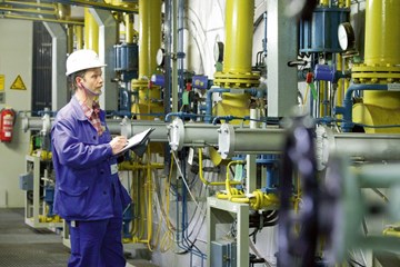 Mann mit Notizblock an Energieerzeugungsanlage Mann mit Notizblock an Energieerzeugungsanlage