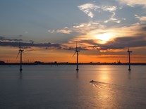 Windkrafträder eines Offshore-Windparks, Sonnenuntergang reflektiert auf dem Wasser Windkrafträder eines Offshore-Windparks, Sonnenuntergang reflektiert auf dem Wasser